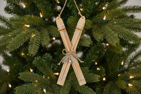 Rustic Crossed Skis Christmas bauble decoration with natural wood finish hanging on a festive tree