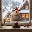 Charming Rustic Reindeer Figurine with a Red Hat and Star Decoration, Set Against a Wintery Background