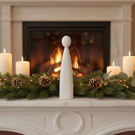 Rustic Standing Angel Decoration on a Mantle Surrounded by Candles and Pinecones for Christmas Room Decorations