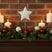 Rustic Star Christmas room decoration with candles, ornaments, and greenery on a mantelpiece
