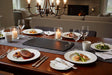 Elegant slate serving tray on a dining table, surrounded by plates of gourmet food