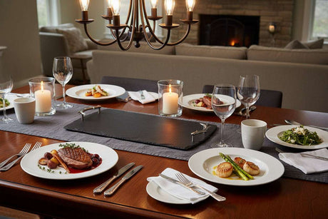 Elegant slate serving tray on a dining table, surrounded by plates of gourmet food