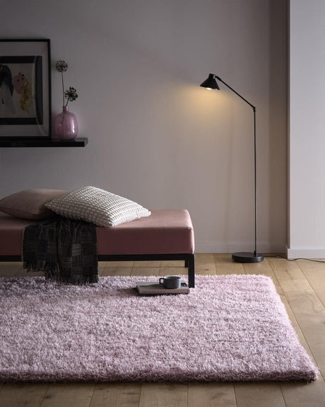 Soft pink Shaggy Rug placed under a minimalist bed with a stylish lamp and decor