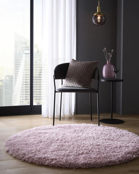 Soft pink shaggy rug placed under a chair in a modern room with a stylish decor