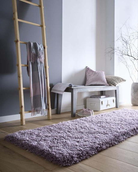 Light purple shaggy rug on wooden floor in modern living space with ladder and bench