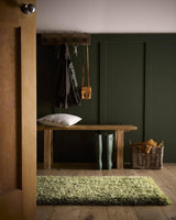 Green Shaggy Rug placed in a hallway with a wooden bench and hooks for coats