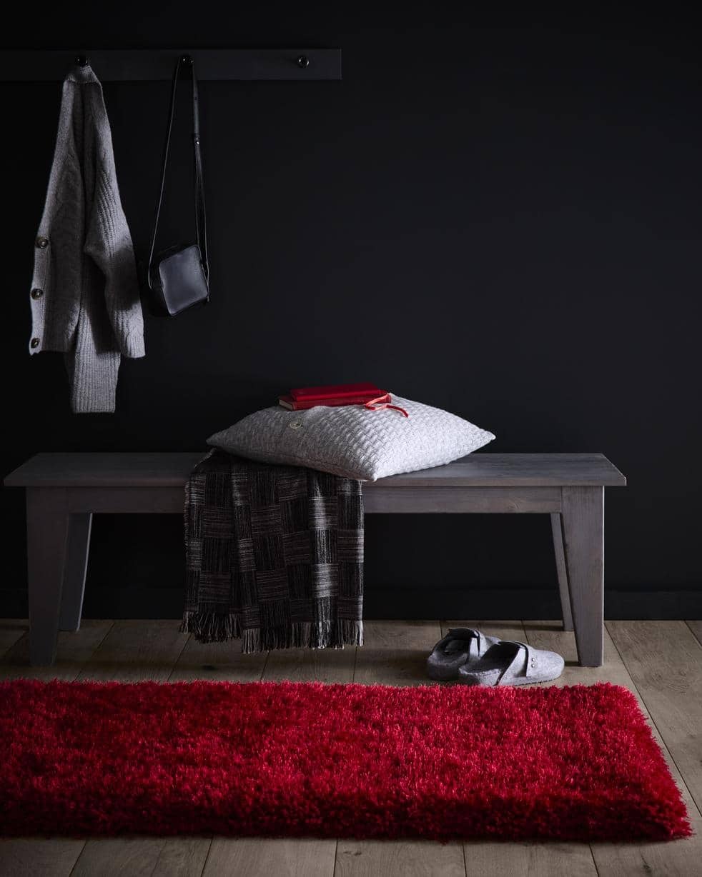 Bold red shaggy rug on wooden floor, enhancing cozy home entryway with stylish decor elements