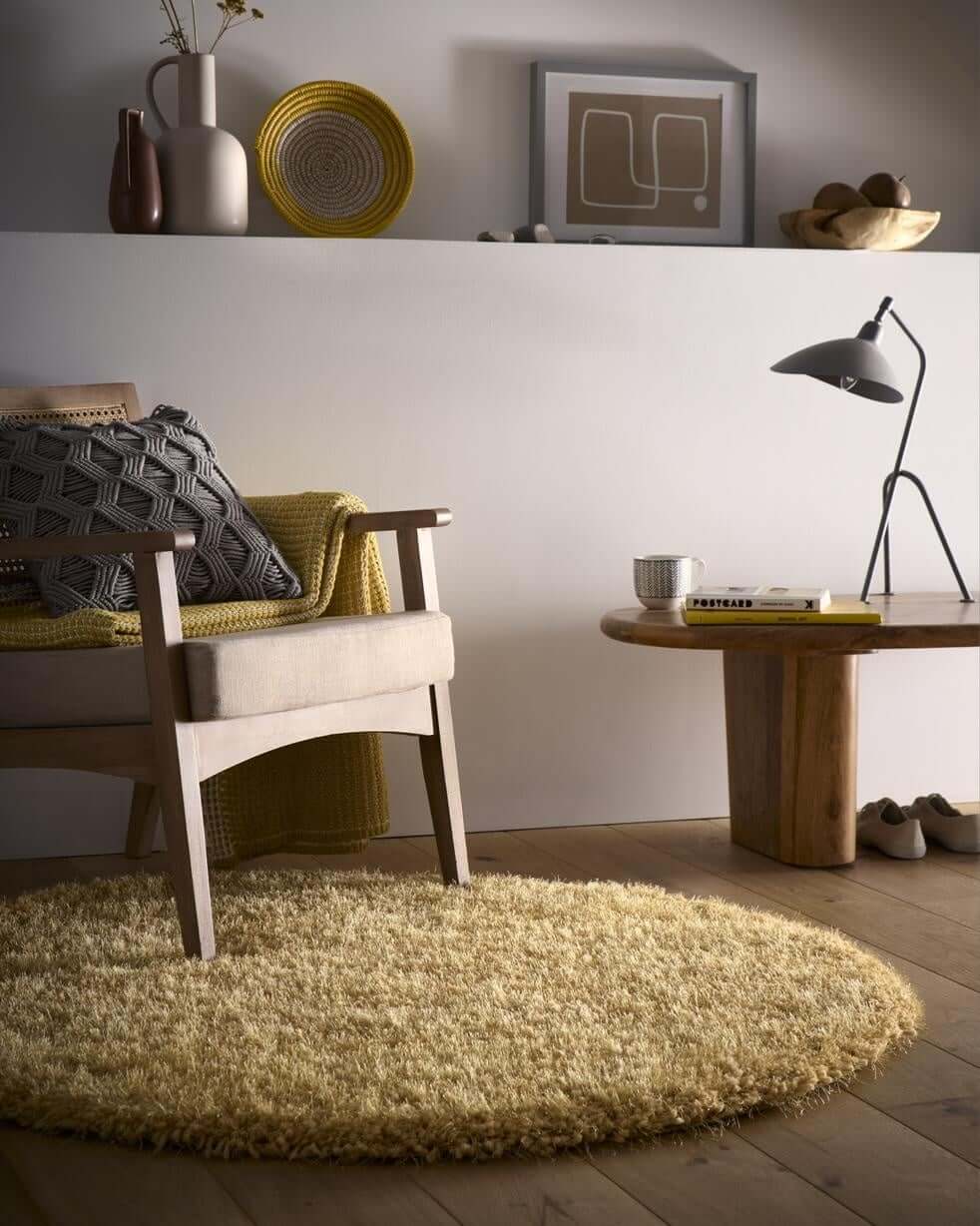 Stylish round shaggy rug in soft yellow, complementing a modern living space with a chair and decor