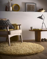 Stylish round shaggy rug in soft yellow, complementing a modern living space with a chair and decor