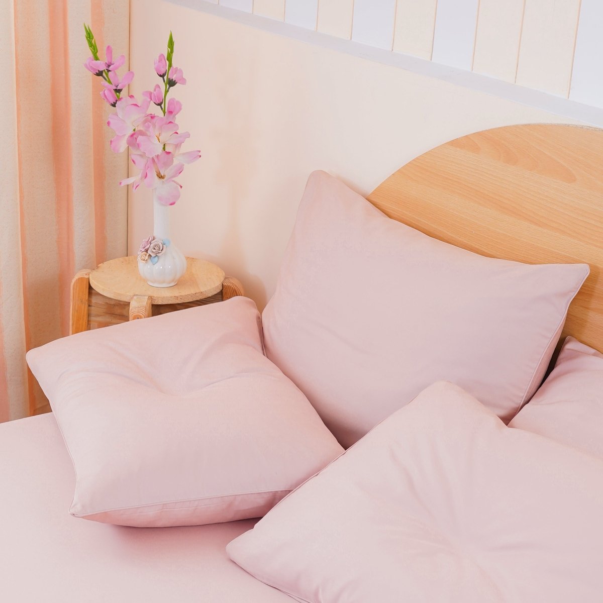 SHEET STORY Soft Pink Bedding Set with Decorative Cushions and Floral Accent on Bedside Table