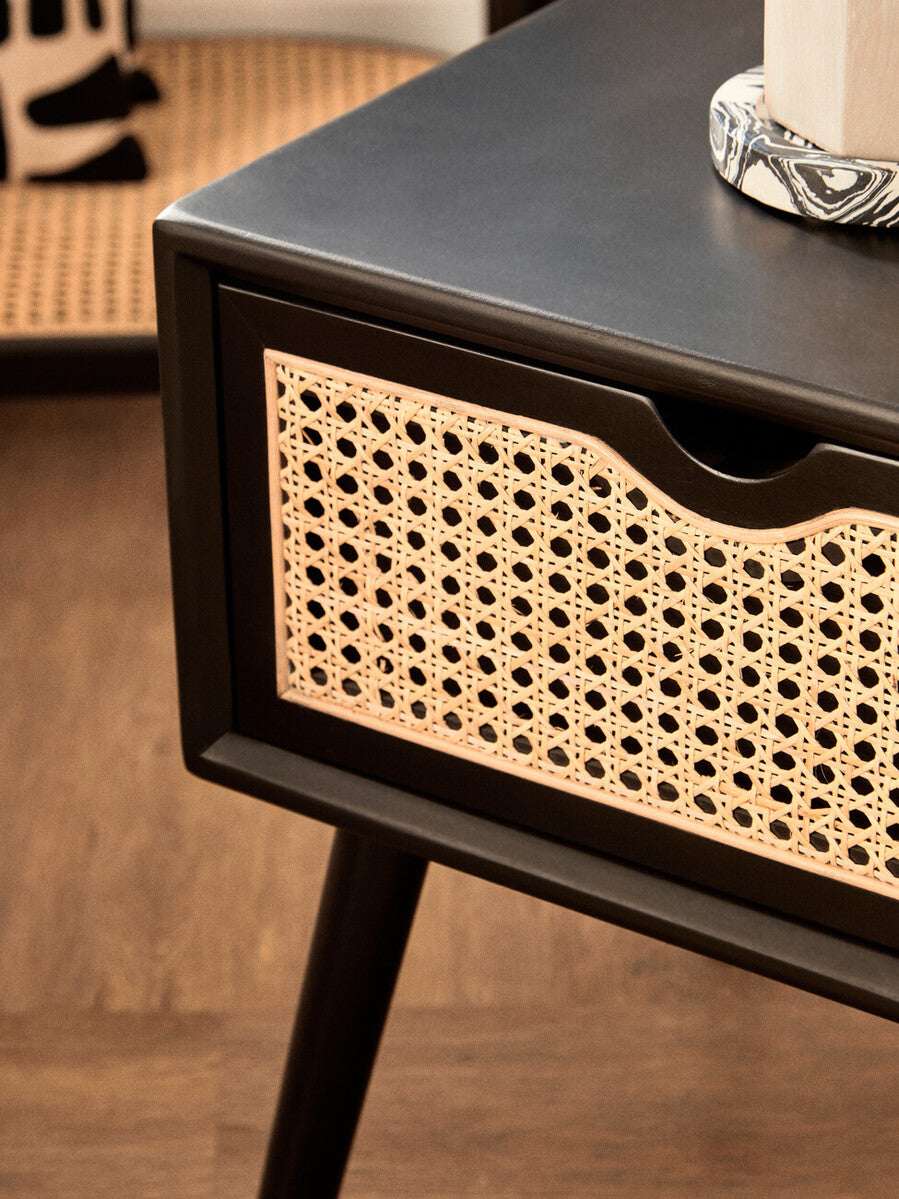 Orsina modern side table featuring a sleek black finish and a stylish cane drawer front