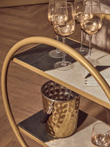 Orsina gold bar cart featuring a side table with wine glasses and a stylish champagne bucket