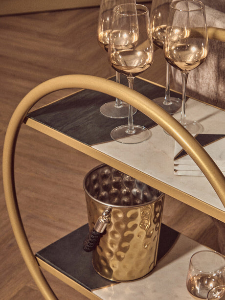Orsina gold bar cart featuring a side table with wine glasses and a stylish champagne bucket