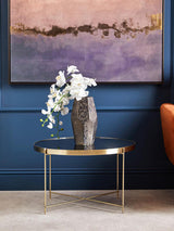 Modern Orsina Side Table with a Gold Base and Glass Top, featuring a flower vase and wall art