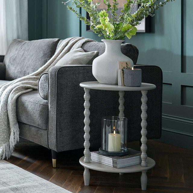 Shades 4 Seasons Side Table with a tiered design, displayed beside a grey sofa and decorated with a vase and candle