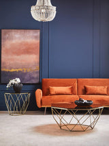 Orsina Side Table with Geometric Design and Gold Finish, placed beside an orange sofa in a stylish living room