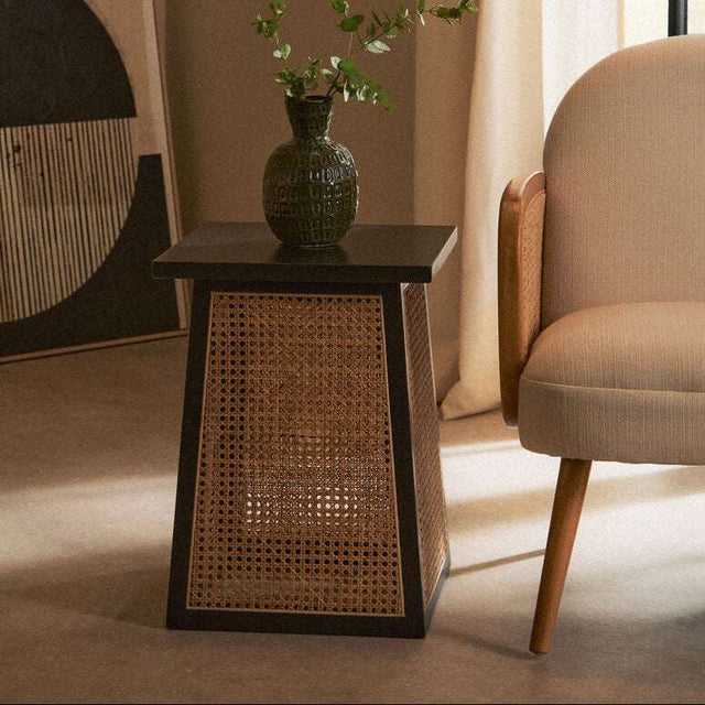 Orsina side table with a wooden top and wicker design, paired with a stylish armchair
