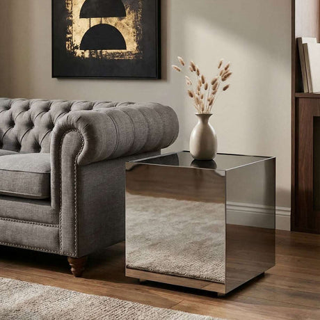 Orsina modern side table with reflective surface beside a grey chesterfield sofa