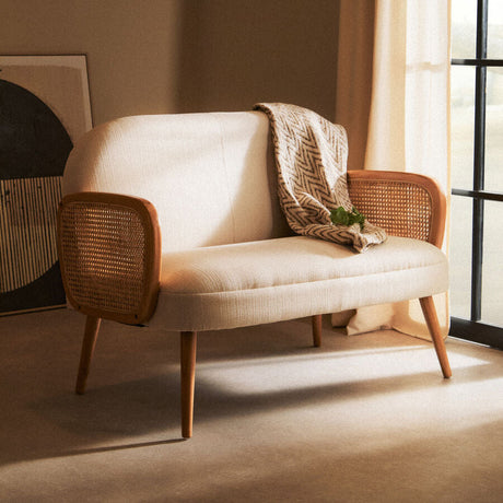 Orsina 2 Seater Sofa in cream with wooden armrests and a cosy blanket draped over it