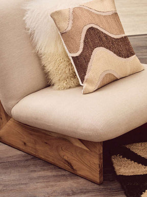 Orsina Square Cushion with a textured design in earthy tones, placed on a stylish chair