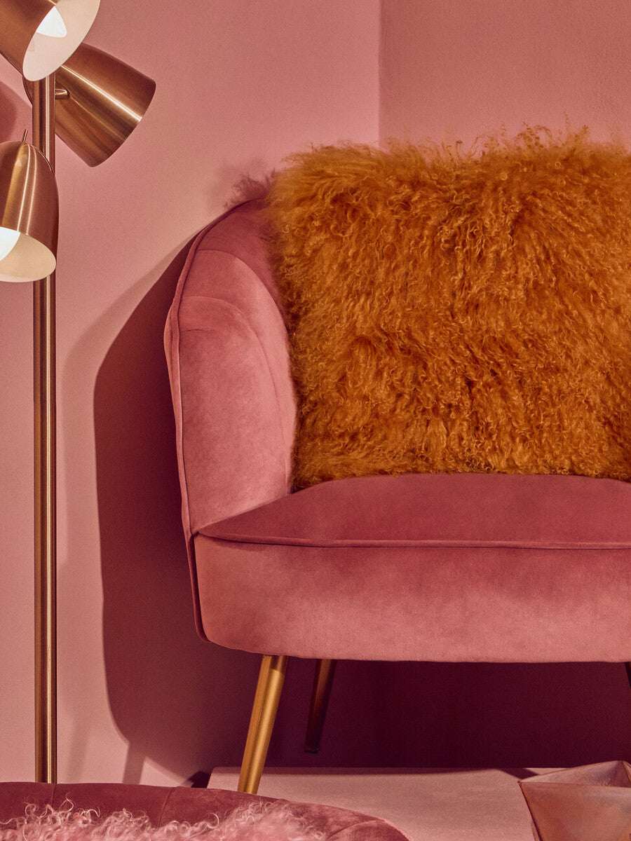 Orsina Square Cushion in a vibrant golden hue placed on a pink velvet chair for stylish decor