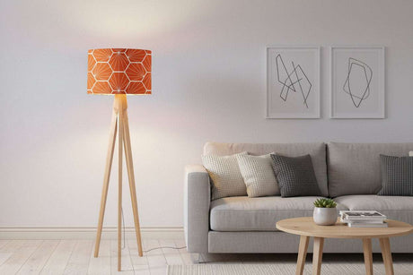 Shadow Bright lampshade featuring an orange geometric design on a stylish tripod floor lamp