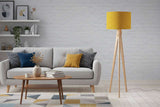 Stylish floor lamp with yellow patterned lampshade and wooden tripod base in modern living room