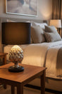 Stylish Orsina Table Lamp with a unique design illuminating a cosy bedroom setting