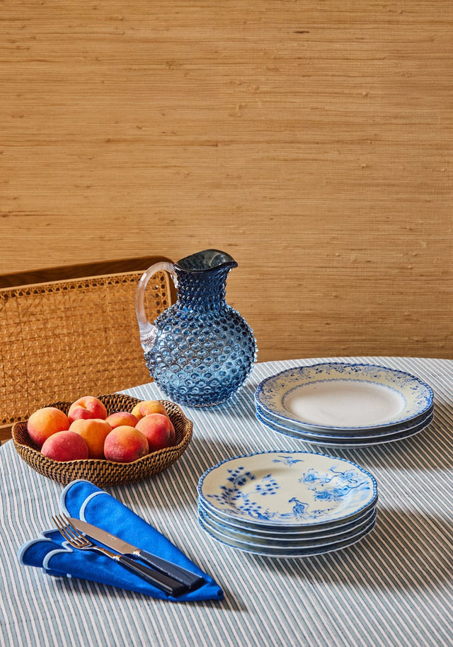 Casa by Josephine Jenno tablecloth with blue and white plates, cutlery, and a pitcher on a striped design