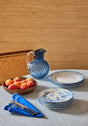 Casa by Josephine Jenno tablecloth with blue and white plates, cutlery, and a pitcher on a striped design