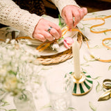 Woman decorating a table with flowers on an elegant Avalon Home UK tablecloth featuring a floral design
