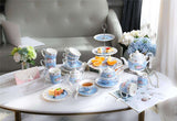 Beautiful blue floral tea set displayed on a table with a cake stand showcasing desserts