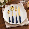 KitchBoom Cutlery Set with Gold Finish and Navy Handles displayed on a White Plate