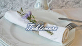 Elegant tableware setting featuring a neatly rolled napkin adorned with flowers beside a delicate tea cup