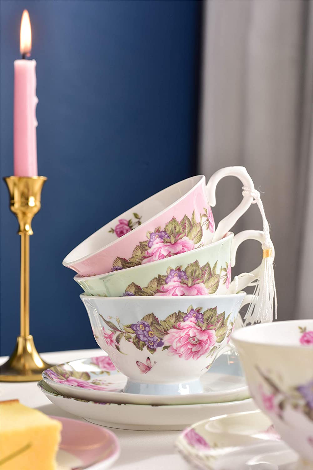 Elegant floral tea cup set in pastel colours stacked on a table with candlelight