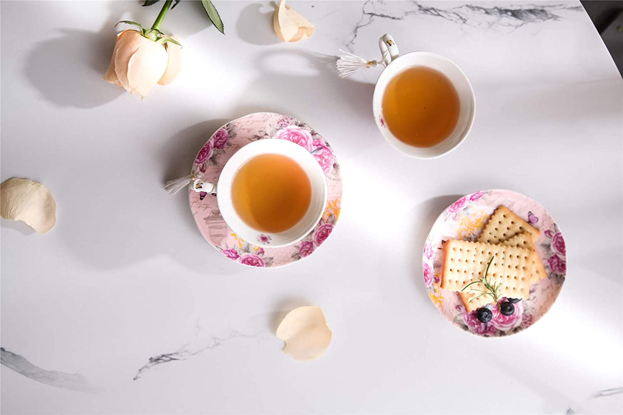 Elegant tea cup with floral design and matching saucer, served with biscuits on a marble table
