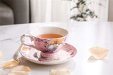Elegant tea cup with floral design alongside a saucer, filled with herbal tea