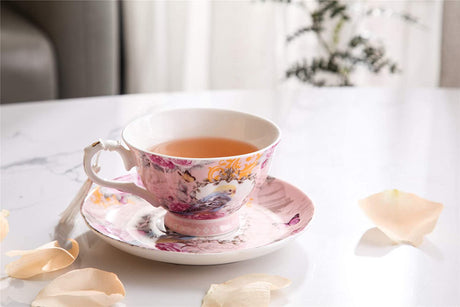 Elegant tea cup with floral design alongside a saucer, filled with herbal tea