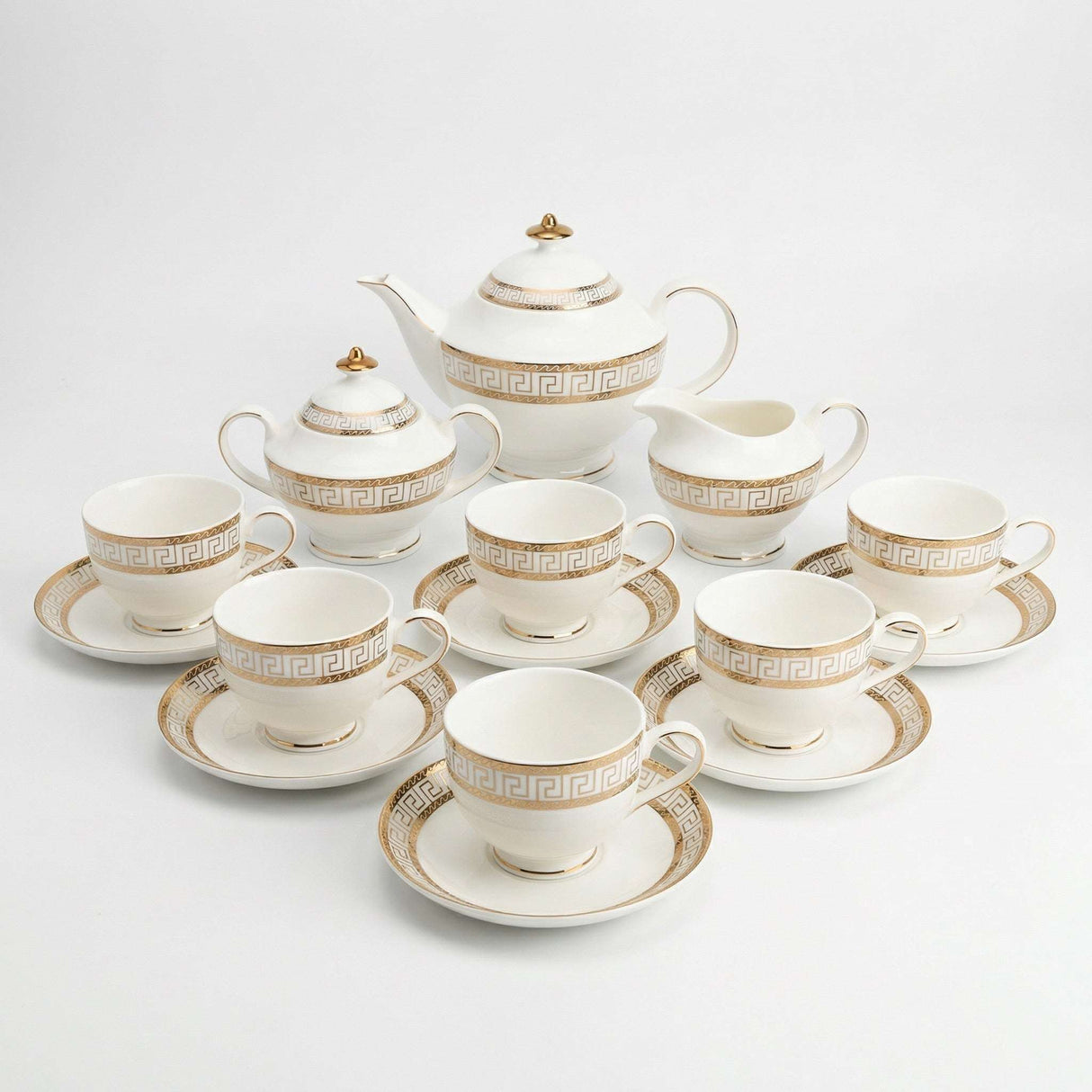 Elegant KitchBoom Tea Set featuring a teapot, cups, and saucers with a gold Greek key design