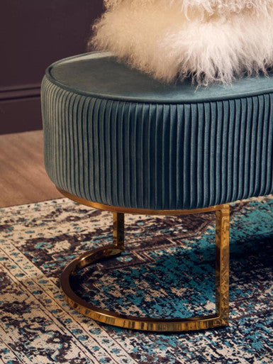 Teal Rug with intricate patterns, placed under a stylish teal ottoman with a gold base