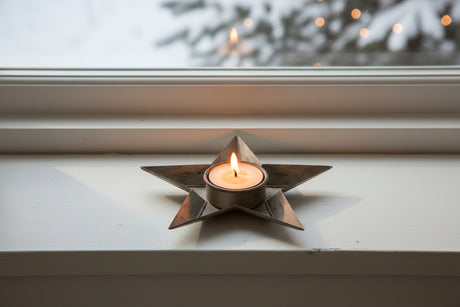 Stylish silver star tealight holder with a candle, perfect for festive Christmas decor