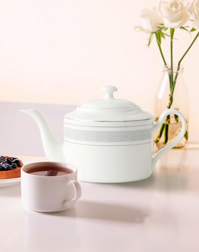 Elegant white Teapot Set with a matching cup and fresh flowers in the background