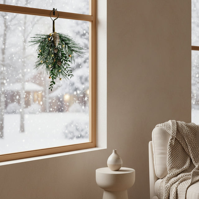 Teardrop Swag artificial greenery decoration hanging in a winter window, adding festive charm to the home