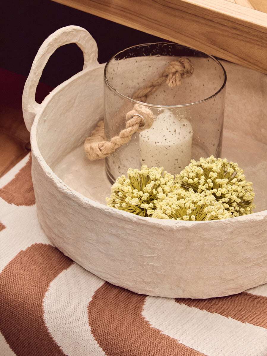 Decorative terracotta throw displayed on a stylish surface with a candle and dried flowers
