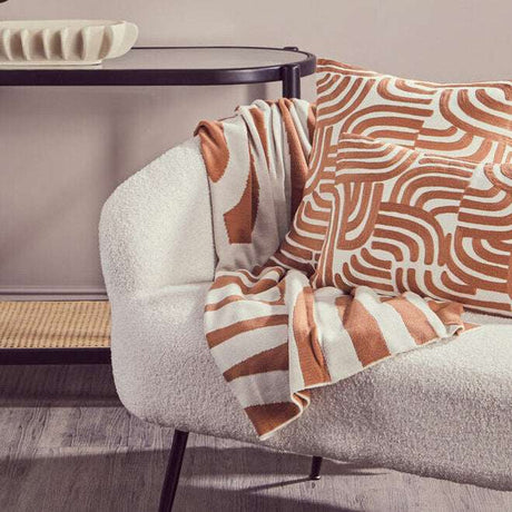 Orsina Terracotta Throw draped over a stylish cream armchair featuring a contemporary pattern