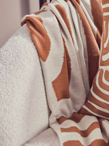 Orsina Terracotta Throw draped over a soft white armchair, featuring a stylish design