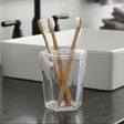 Orsina Toothbrush Holder with three bamboo toothbrushes in a clear geometric container