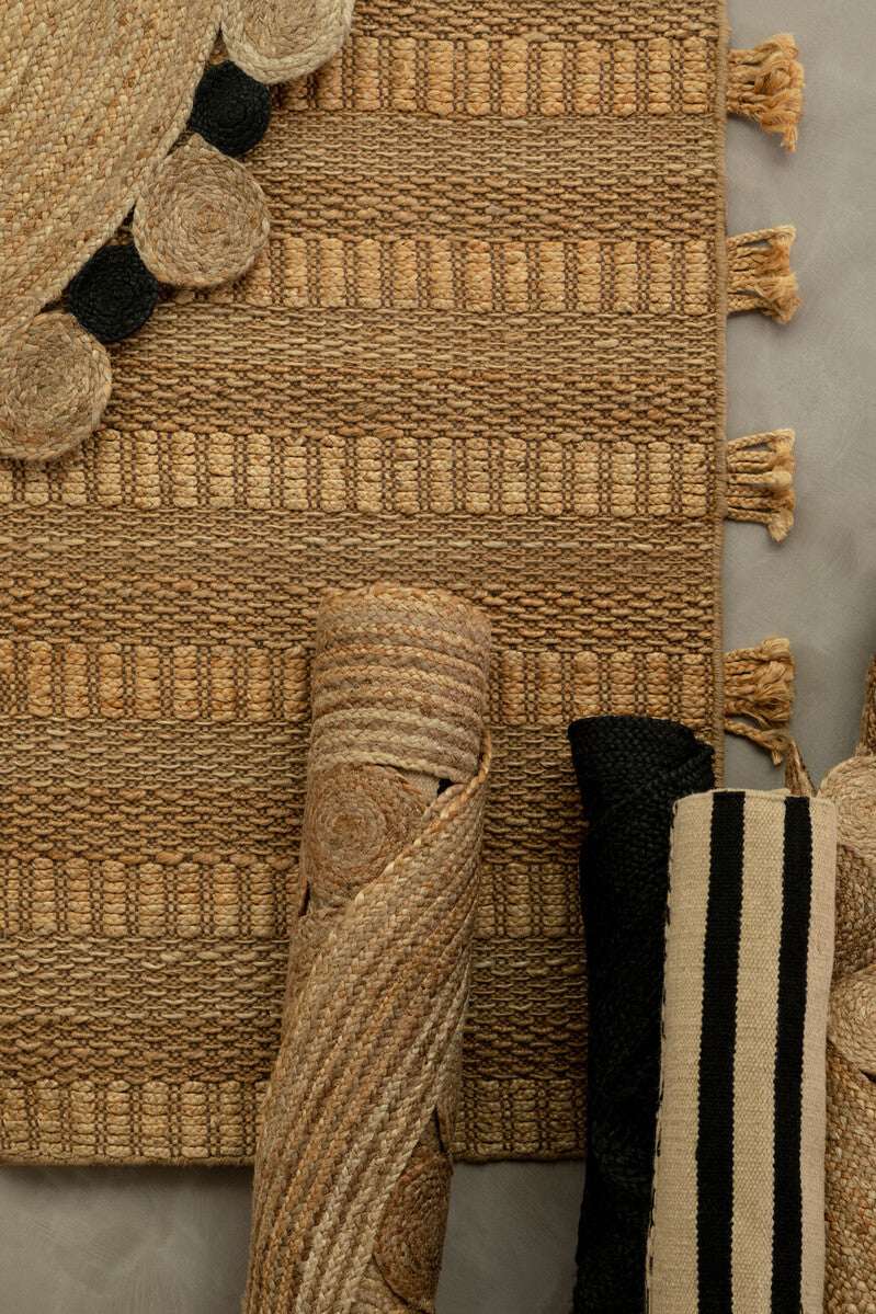 Orsina Trenza Rug featuring a textured natural design with tassels and rolled rugs in various patterns