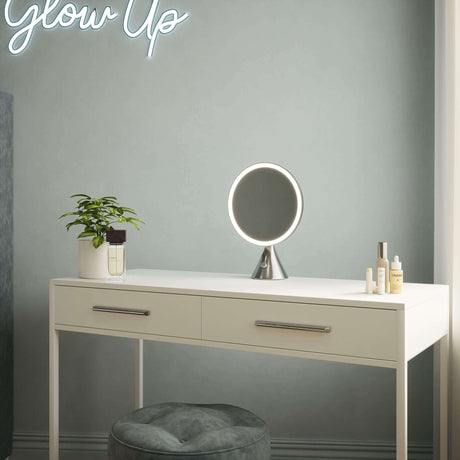 Stylish vanity mirror on a white dressing table with skincare products and a plant