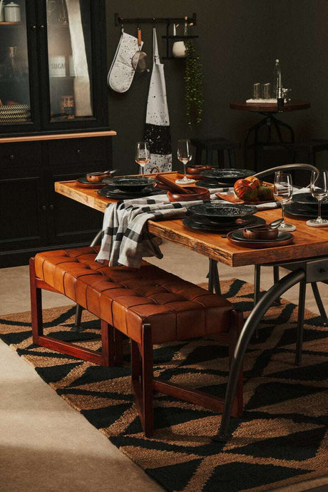 Stylish dining area featuring an Orsina Hemp Rug beneath a wooden table and leather bench